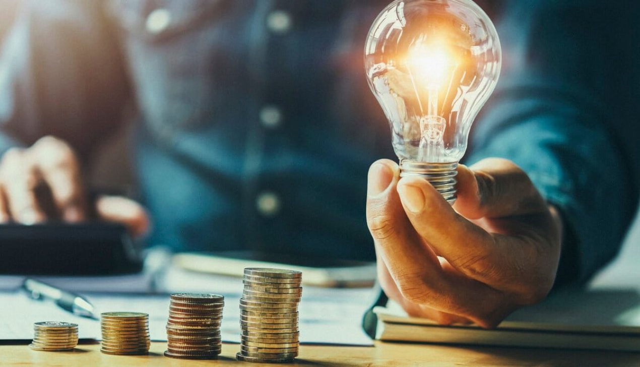business man hand holding lightbulb with using calculator to cal business man hand holding lightbulb with using calculator to calculate and money stack. idea saving energy and accounting finance in office concept