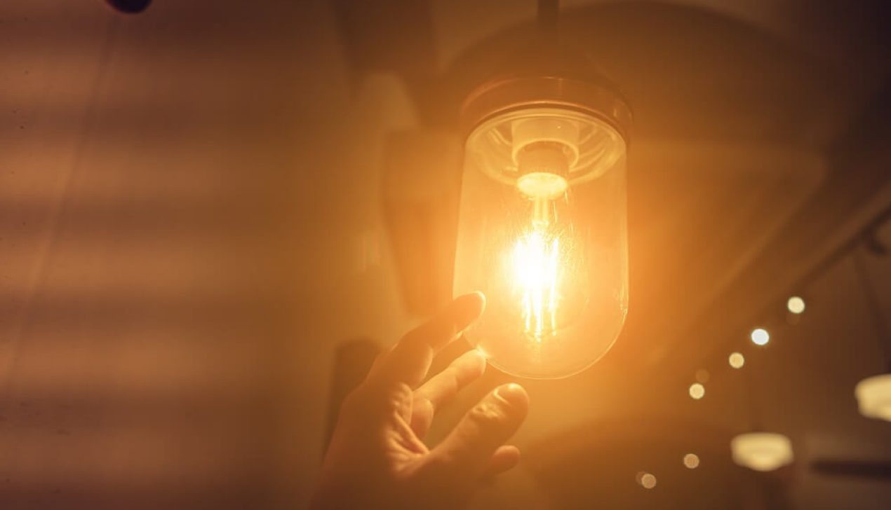 Hand reaching for a vintage light bulb. Hand reaching for a vintage light bulb. Dark and abstract concepts